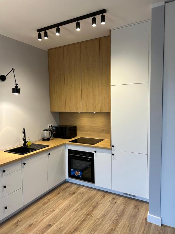 a kitchen with white cabinets and wood floors at Apartament 5 piętro in Częstochowa