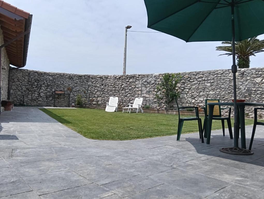 a patio with a table and chairs and an umbrella at Casa ROSAMUNDA con gran jardín y cerca del mar in Santander
