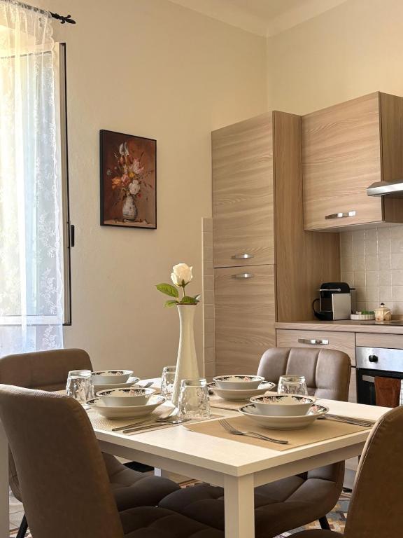 a dining room table with chairs and a vase with flowers at Trilocale a 100 m dal mare in Imperia