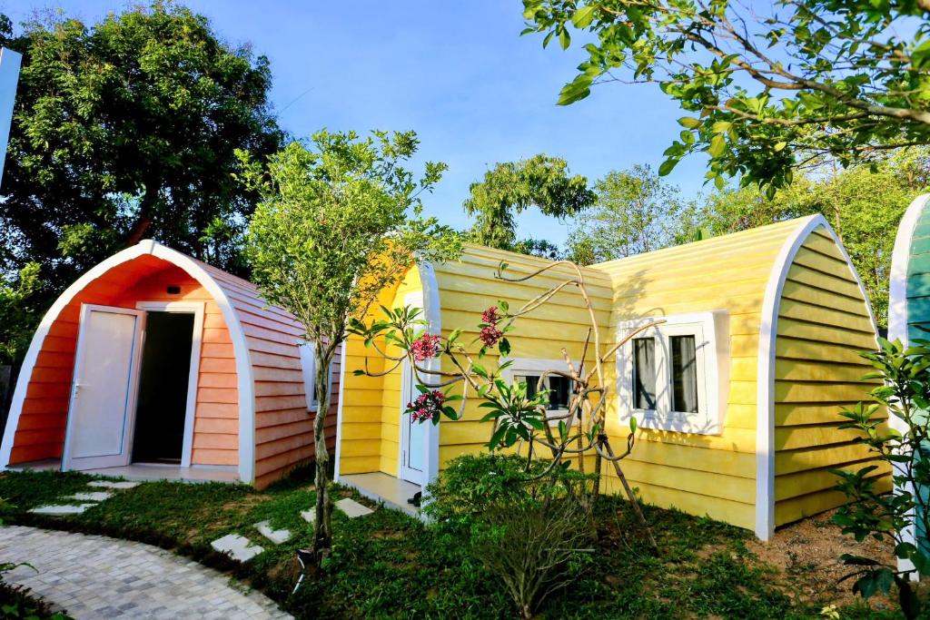 une petite maison jaune avec une porte rouge dans l'établissement Minh Hầu Lạc Trú Homestay, à Ấp Long Hồ Hạ