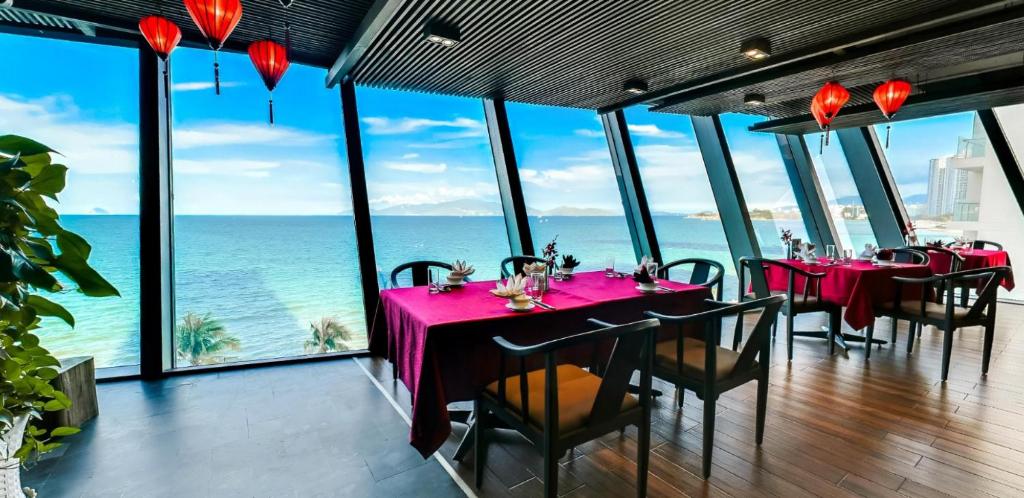 a dining room with tables and chairs and the ocean at Boton Blue Hotel & Spa in Nha Trang