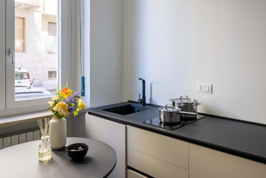 a kitchen with a sink and a table with flowers at La Casa del Bersagliere - STUDIO in Biella