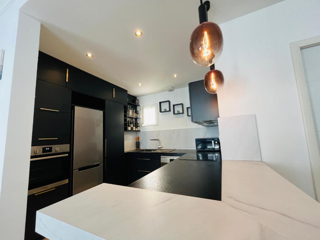 Una cocina con gabinetes negros y una encimera blanca. en Îlot lac Central et moderne, en Annecy
