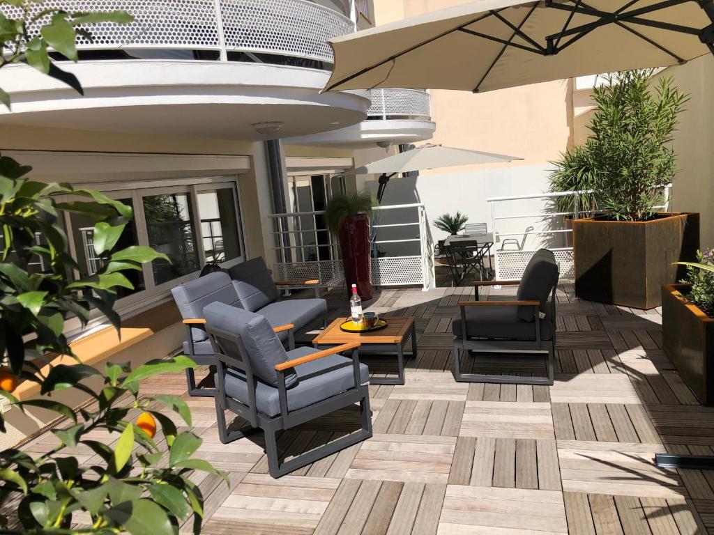 une terrasse avec des chaises, des tables et un parasol dans l'établissement Superbe T2 avec Wifi, terrasse 100m², parking au centre d'Arcachon - FR-1-374-207, à Arcachon