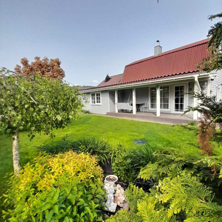 a white house with a red roof and a yard at Jaukus namas šalia Klaipėdos in Kiškėnai