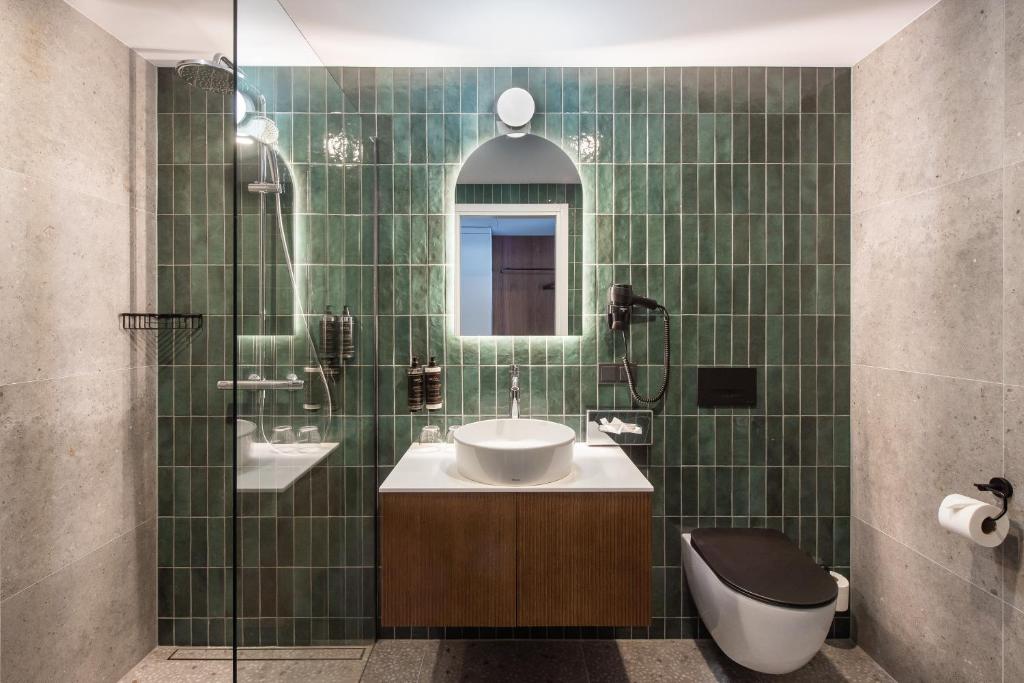 a green tiled bathroom with a sink and a shower at AIRINN Vilnius Airport Hotel RENOVATED 2025 in Vilnius