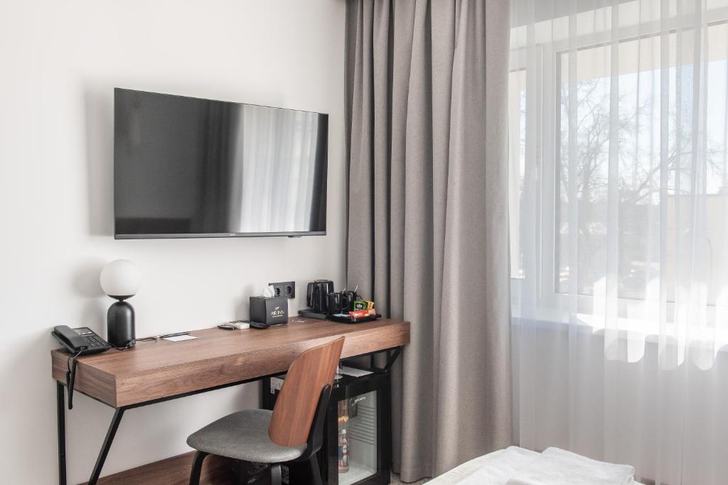 a room with a desk with a television on the wall at AIRINN Vilnius Airport Hotel RENOVATED 2025 in Vilnius