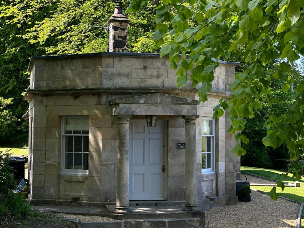 a small stone building with a white door at Meldon Park Gate Lodge in Hartburn