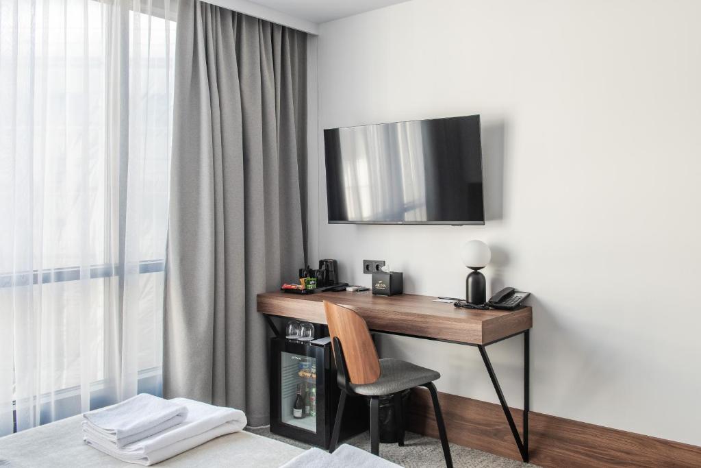a room with a desk with a television and a chair at AIRINN Vilnius Airport Hotel RENOVATED 2025 in Vilnius
