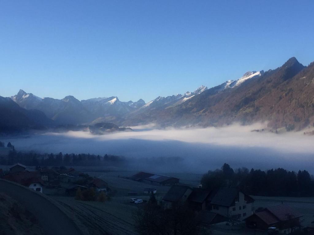 a foggy valley with mountains and houses in the foreground at Au Chant des Grillons - studio ensoleillé en Gruyère in Estavannens-Dessous