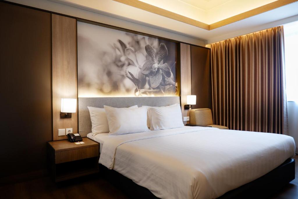 a large bed in a hotel room with a painting at Orchardz Jayakarta in Jakarta