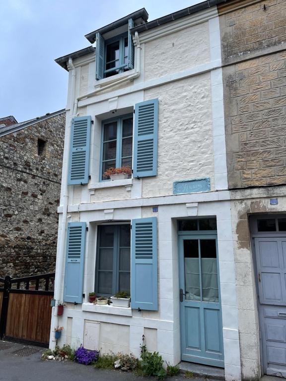 une vieille maison avec des volets et des fenêtres bleus dans l'établissement Maison de pêcheur petite vue mer centre village, à Villerville