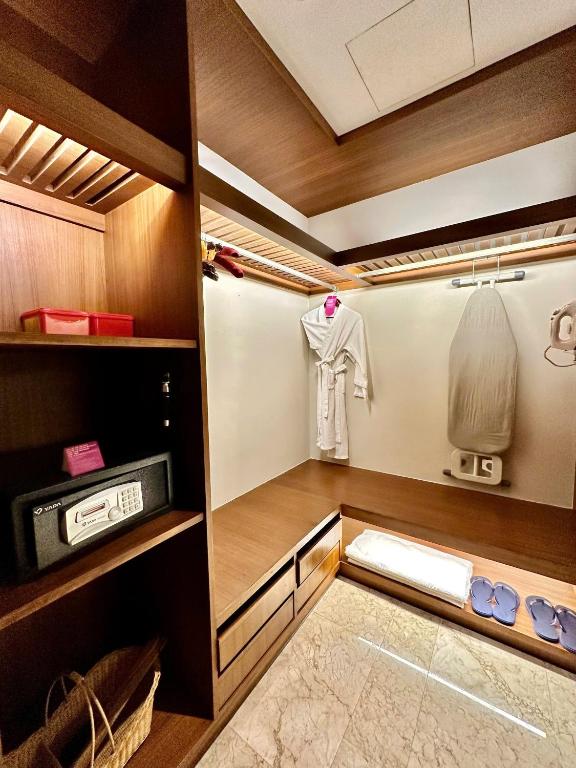 A wood-lined walk-in wardrobe includes hanging space, drawers, a safe and an ironing board.