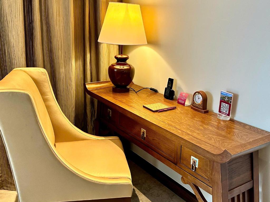A traditional wooden desk beside a cushioned chair and reading lamp.
