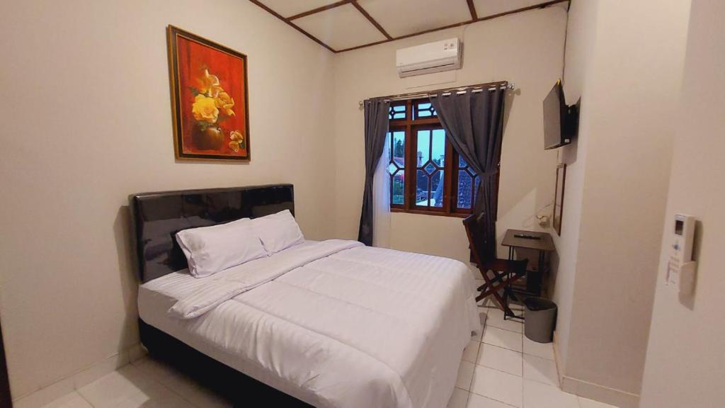 een slaapkamer met een bed met witte lakens en een raam bij Agni Homestay in Timuran