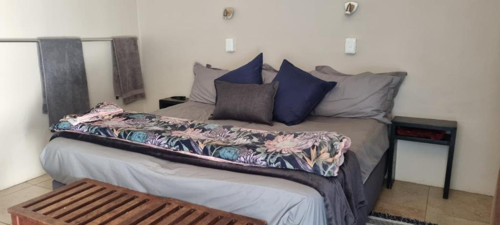 een slaapkamer met een bed met blauwe en paarse kussens bij Cookhouse Cottages in Vosburg