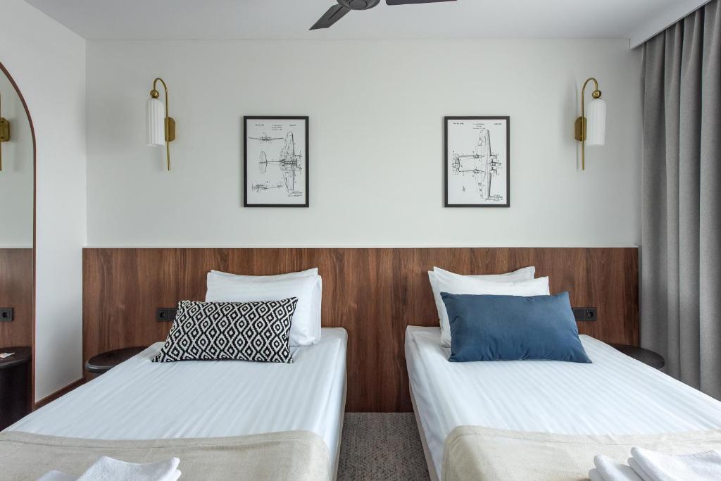 two beds in a room with white and blue pillows at AIRINN Vilnius Airport Hotel RENOVATED 2025 in Vilnius