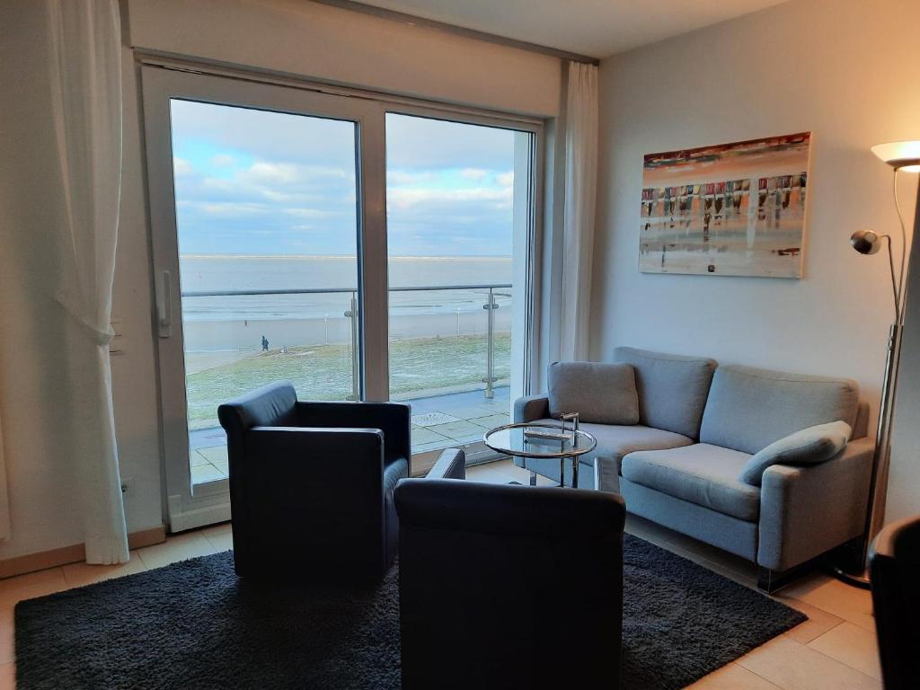 un soggiorno con divano e sedie e vista sulla spiaggia di Penthaus 15 Strandvilla Therese a Norderney