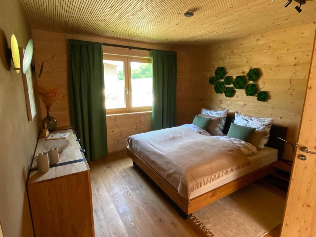a bedroom with a bed with green curtains and a window at NaturWohnRaum - Urlaub im Holzhaus in Berg am Starnberger See