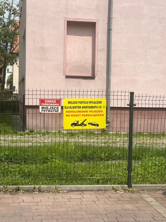 a fence with signs on it in front of a building at Apartament LUCA in Oleśnica