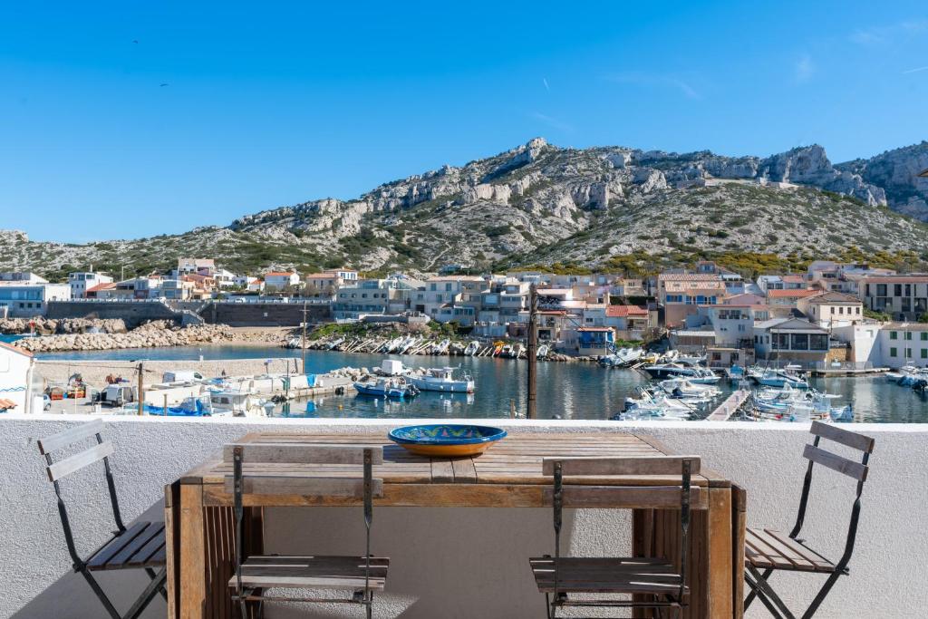 d'une table et de chaises sur un balcon avec un port. dans l'établissement Maison de charme au coeur des Goudes 5 pers, à Marseille