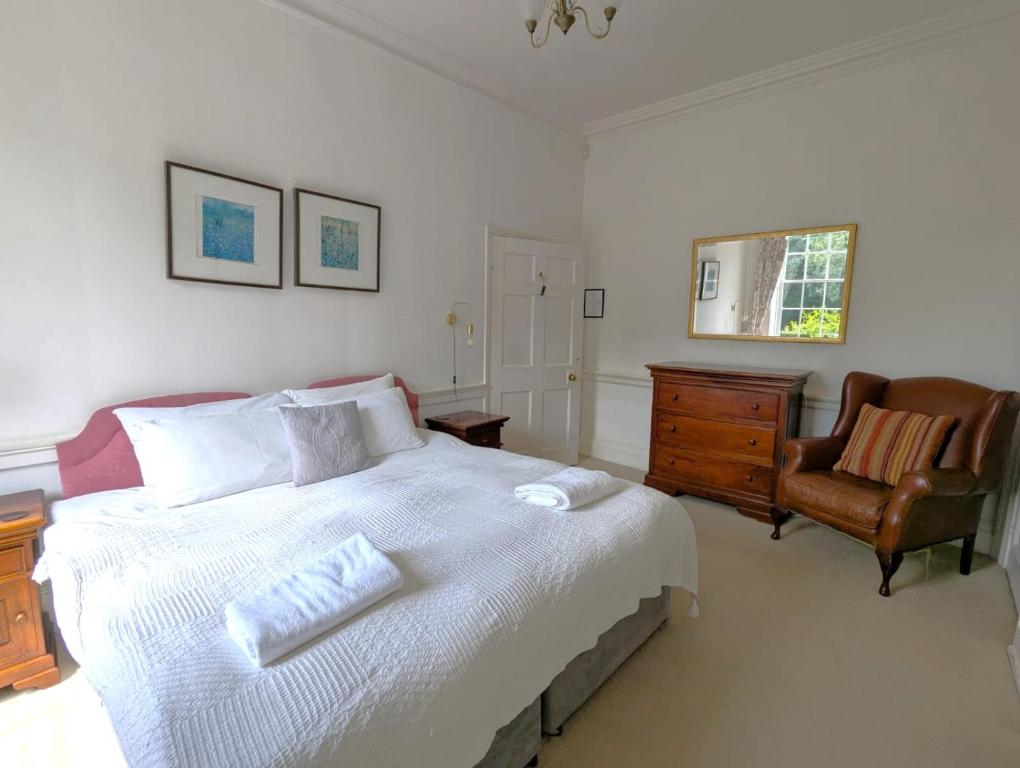 a bedroom with a large white bed and a chair at East Pallant Bed and Breakfast, Located in Large Georgian Townhouse in Central Chichester in Chichester