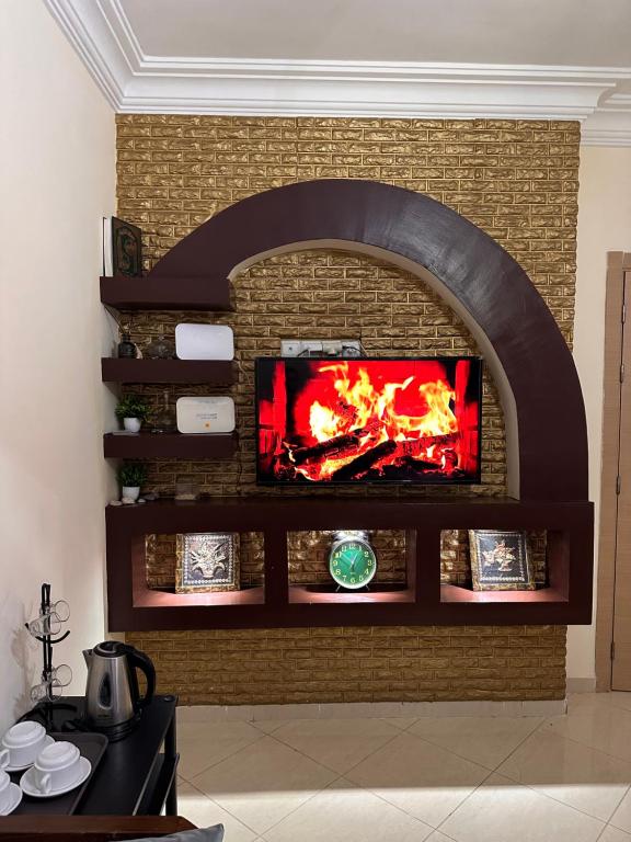 a fireplace with a tv on a brick wall at Échappez à la ville , Appartement près de la nature, entre forêt et plage juste pour les familles in Skhirat