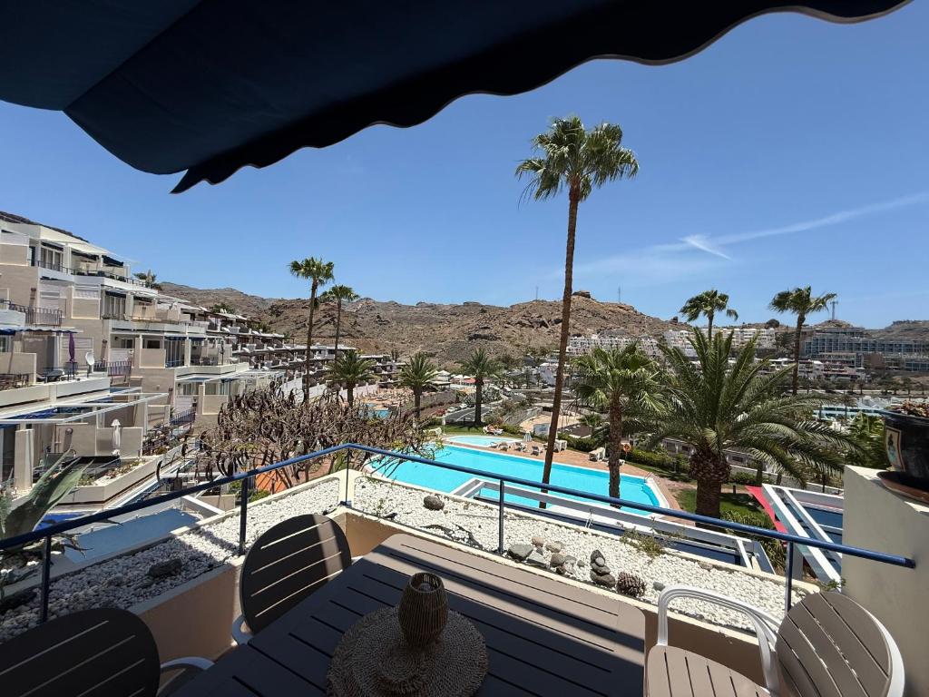 Un balcón con vista a la piscina y palmeras. en Lovisi Suite Playa del Cura - OCEAN & POOL VIEW, en Mogán