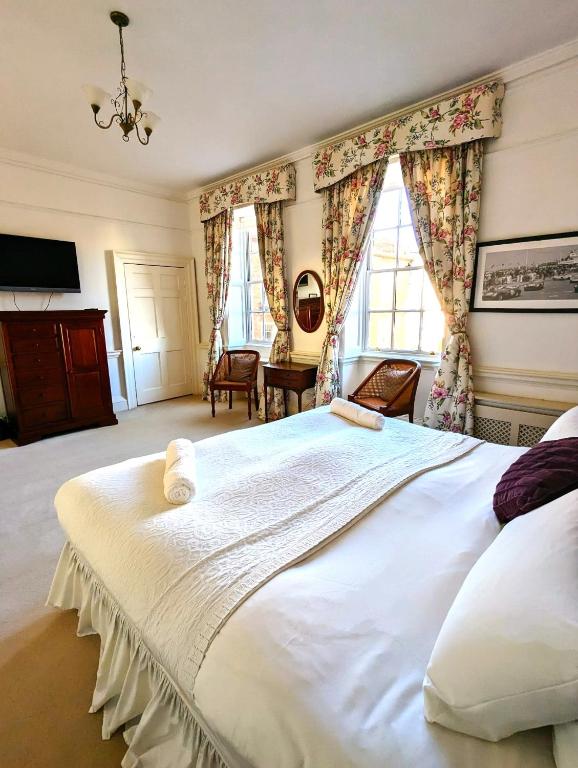 a large white bed in a room with windows at East Pallant Bed and Breakfast, Located in Large Georgian Townhouse in Central Chichester in Chichester