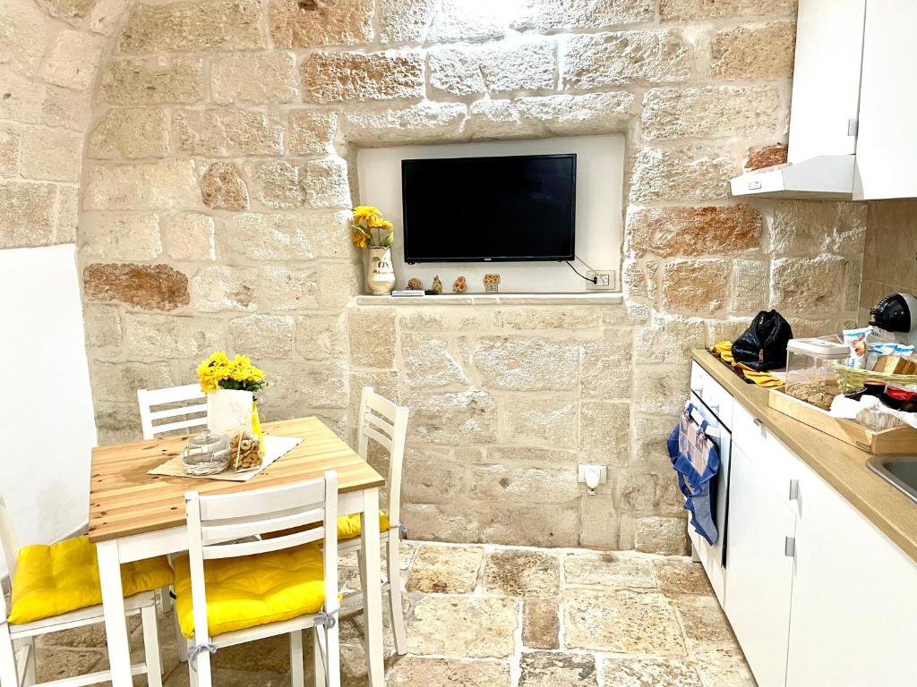 a kitchen with a table and a tv on a stone wall at Antica Pietra in Polignano a Mare