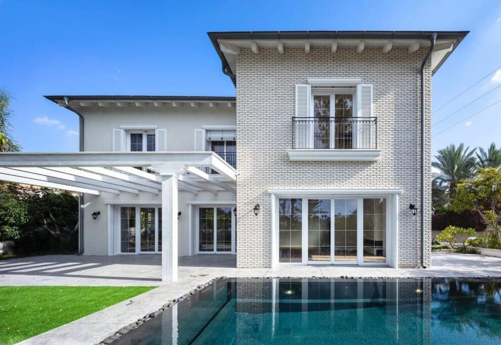 a house with a swimming pool in front of a house at Carmelo Congress Villa in Herzliya Pituah
