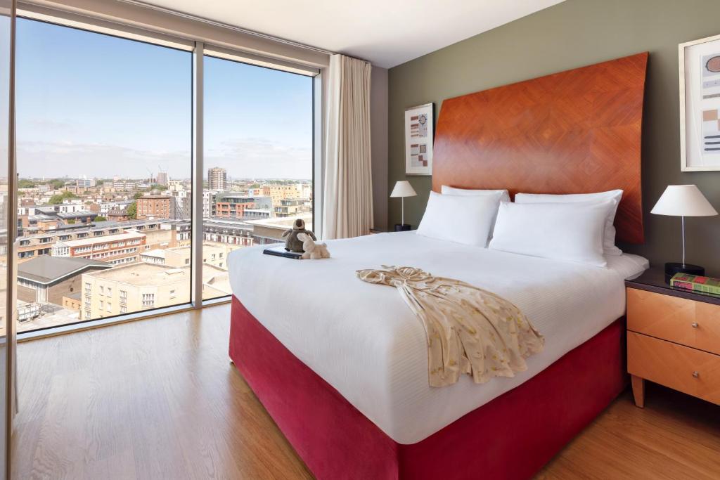a hotel room with a large bed and a large window at Marlin Aldgate Tower Bridge in London