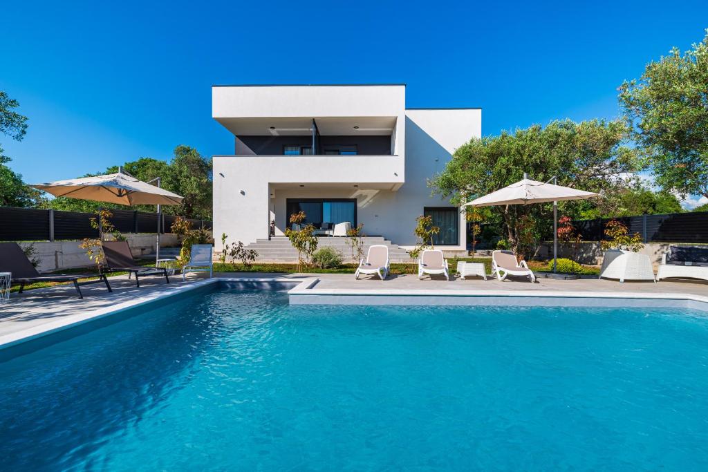 a villa with a swimming pool in front of a house at Apartment Vista Mare 2 with heated pool in Sveti Filip i Jakov