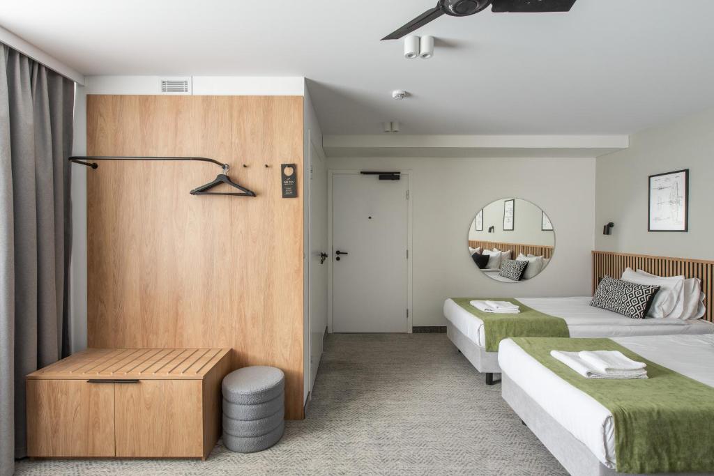 a hotel room with two beds and a mirror at AIRINN Vilnius Airport Hotel RENOVATED 2025 in Vilnius