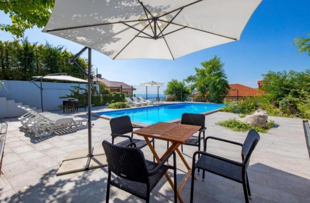a patio with a table and chairs and an umbrella at Apartman Lea - Villa Oleander in Ičići