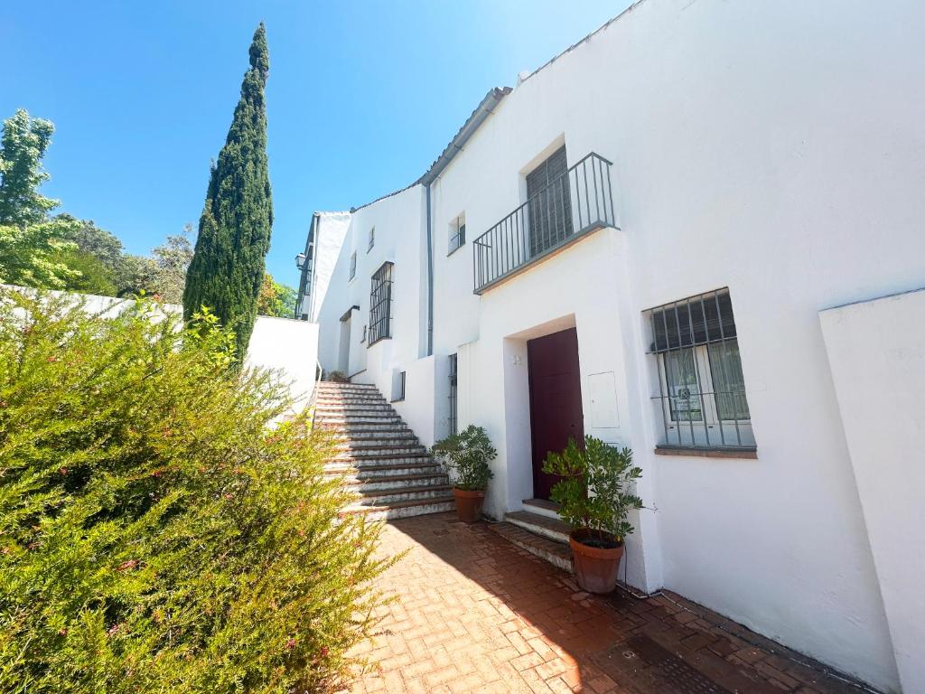 un edificio blanco con escaleras y una puerta en La Casita de San Gonzalo, en Higuera de la Sierra