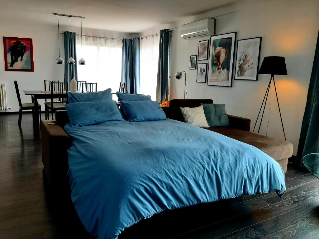 - une chambre avec un grand lit bleu et un canapé dans l'établissement Couchage solo ou à 2 avec grand salon à Perpignan, à Perpignan