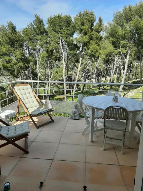 un patio avec une table, des chaises et des arbres dans l'établissement Appartement avec Mezzanine dans résidence boisée, à La Ciotat