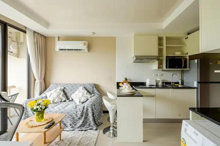 Una pequeña sala de estar con un sofá y una cocina. en Room 402 Rawai Beach Condo, en Nai Harn Beach