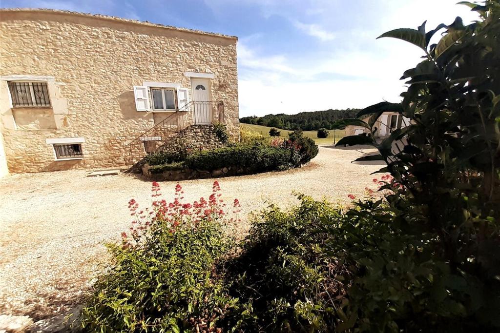 une maison en pierre avec un jardin en face dans l'établissement Le Moulin aux Lavandes, à Redortiers