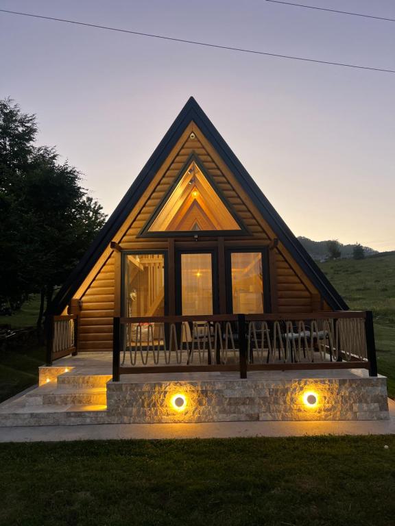 a log cabin with a porch and some lights at Grlo Sokolovo A-Frame Cottage - Mountain Retreat near Podgorica in Korita
