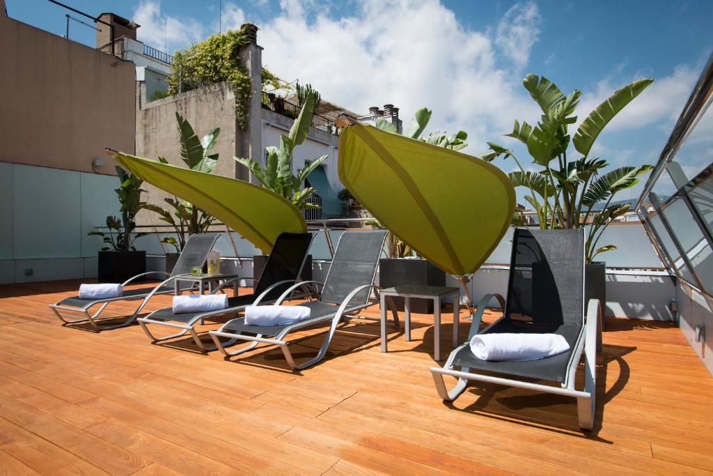 un grupo de sillas y sombrillas en un techo en Ako Suite Hotel, en Barcelona