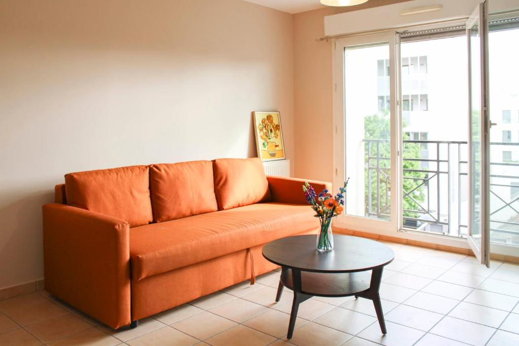 - un canapé orange dans le salon avec une table dans l'établissement Apartment with balcony near the city center, à Saint-Denis