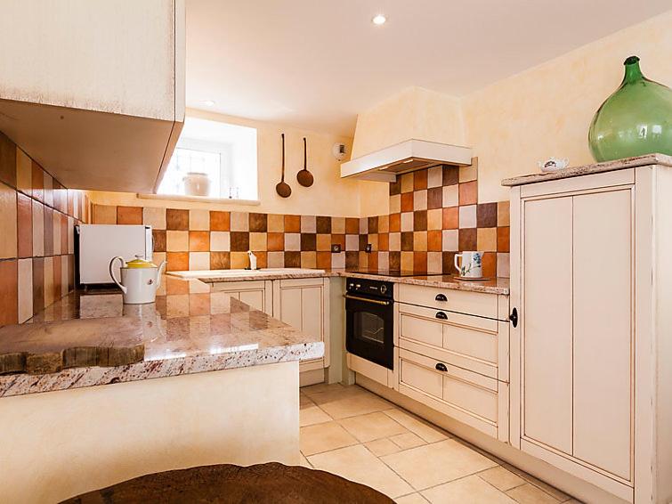 une cuisine avec des placards blancs et un vase vert dans l'établissement La Bergerette de Pierroun, à Redortiers