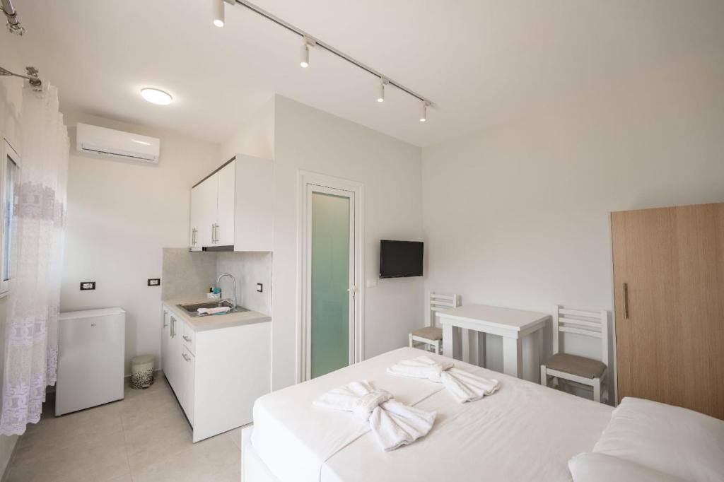 a white room with a bed and a kitchen at Vila Celi in Sarandë