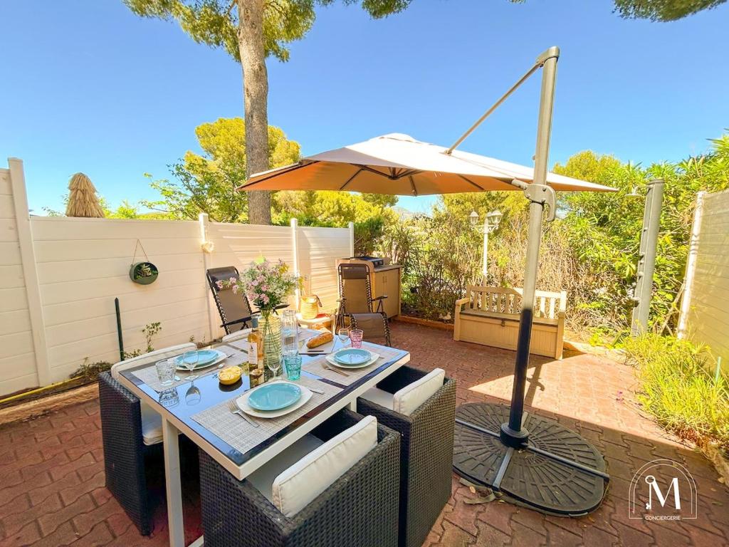 - une table avec un parasol sur la terrasse dans l'établissement Coquet T2 à Sanary-sur-mer en rez-de-jardin, à Sanary-sur-Mer