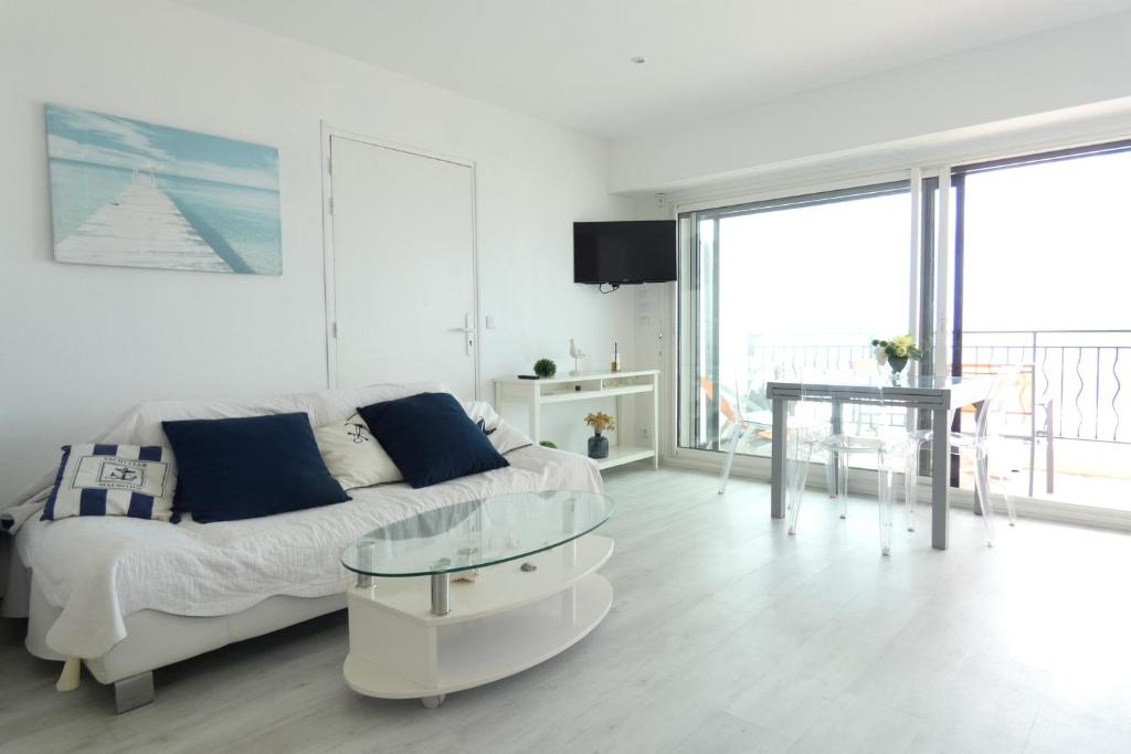 un salon blanc avec un canapé et une table dans l'établissement Ocean vert - front de mer - balcon, à La Baule