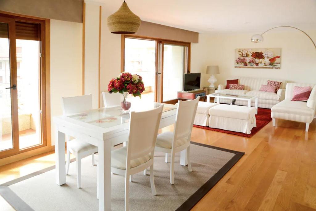 Una sala de estar con una mesa y sillas blancas. en P17 Nuevo Atico Isla de la Toja, en O Grove