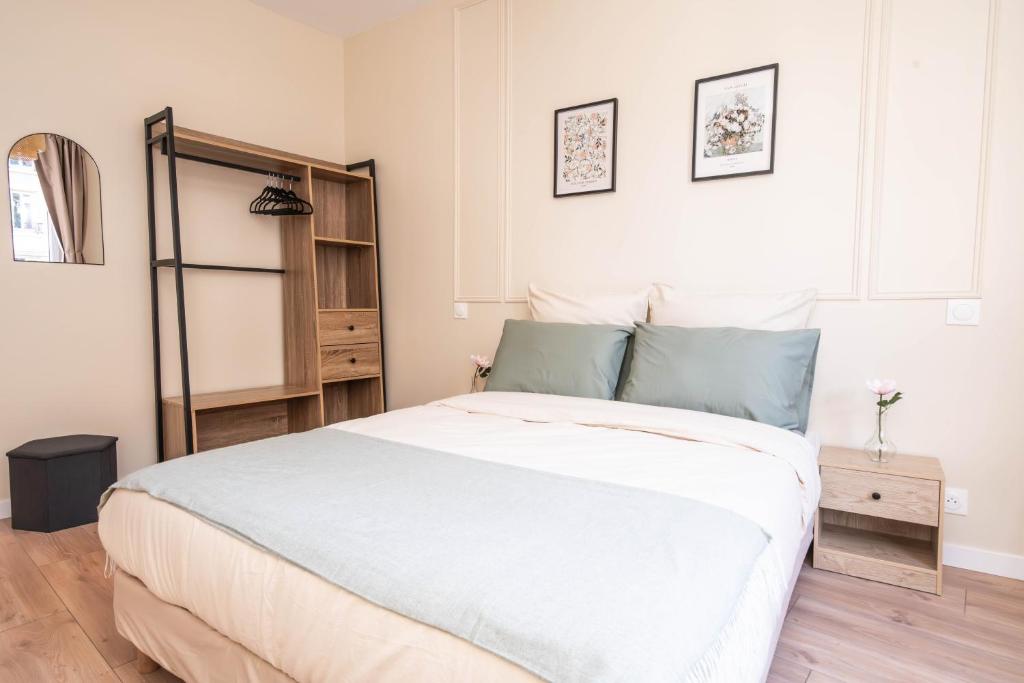 - une chambre avec un grand lit blanc et une étagère dans l'établissement Le petit Haussmann, à Clichy