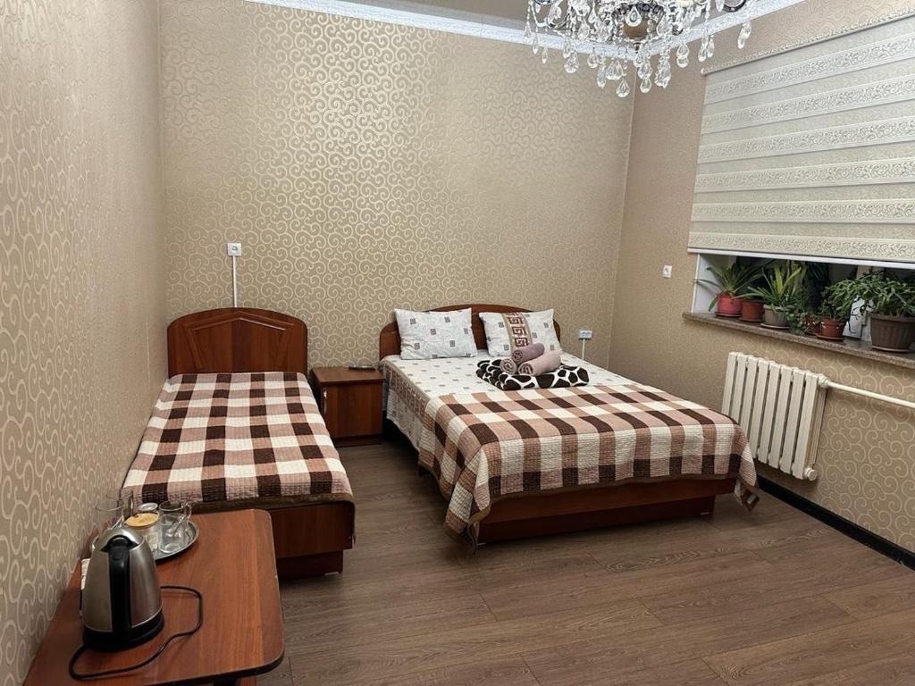 a bedroom with two beds and a table and a chandelier at Lotos Guest House in Bishkek